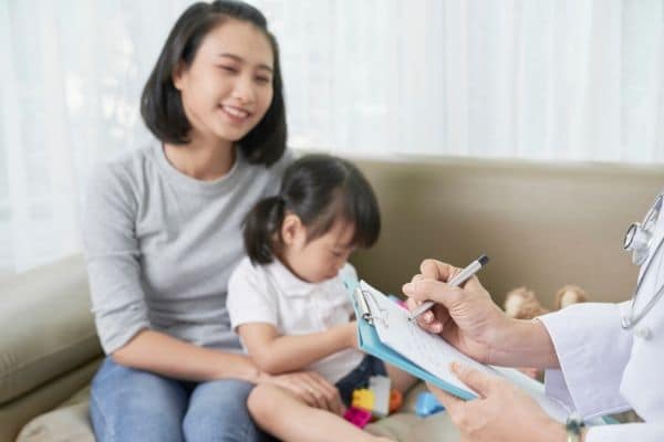 A woman and her daughter with a doctor during a routine checkup.