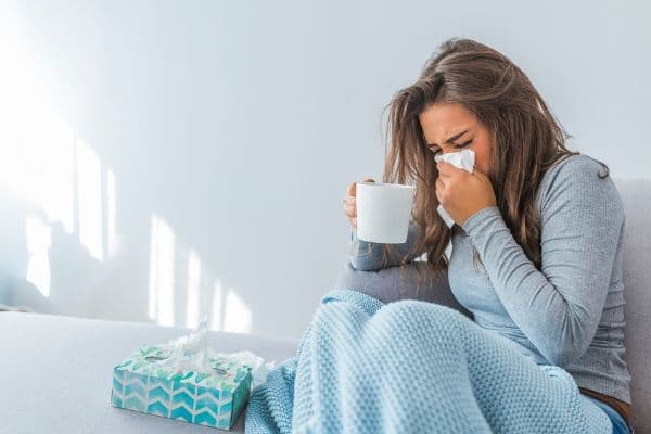 A young woman blowing her nose during a cold