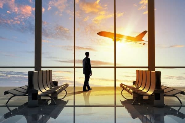 A man standing against the window of an airport.