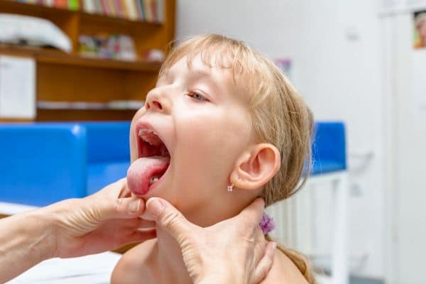 A young girl having her throat examined during a exam.