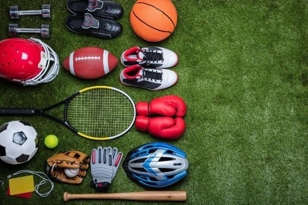 A large assortment of sports gear and acessories laying against a football field.